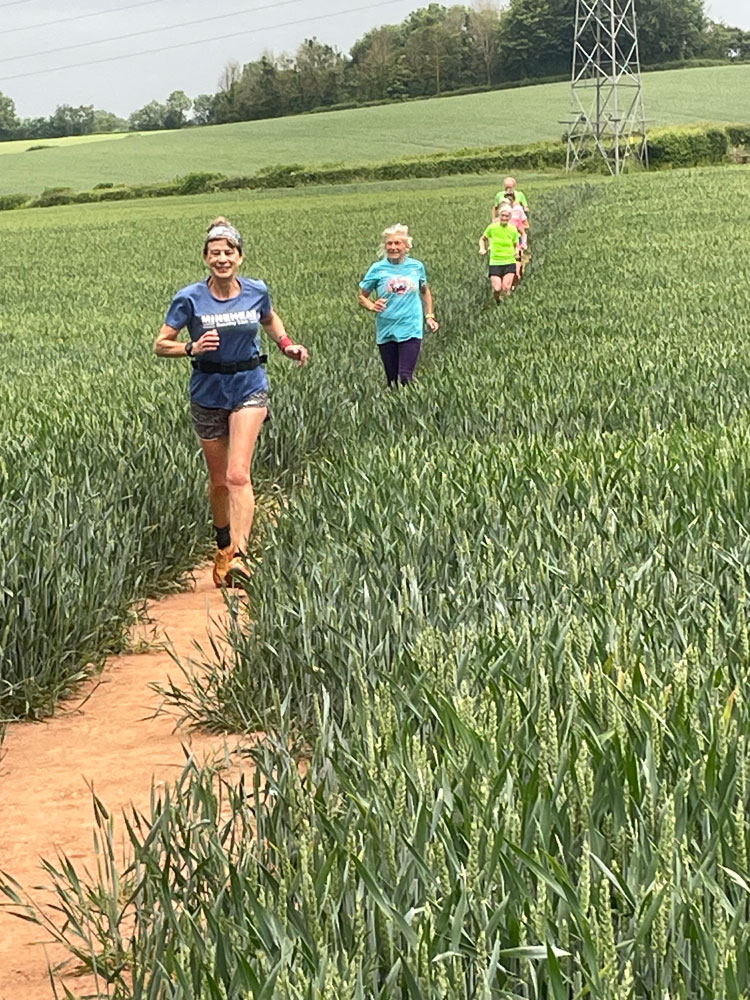 Minehead Club runners together running across a field of wheat