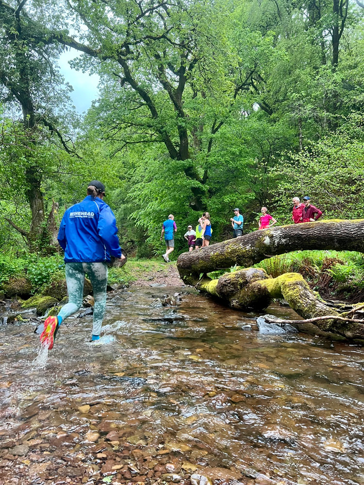 People running through a river with Minehead Running Club